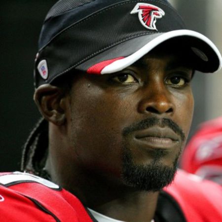 Michael Vick in a red jacket and black cap caught at the camera.